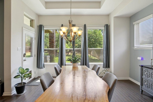 dining area with dark wood finished floors, baseboards, a notable chandelier, and a tray ceiling