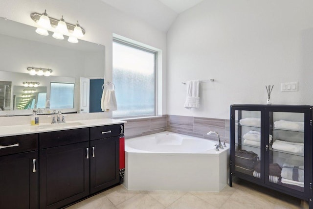 full bath with a bath, tile patterned floors, vaulted ceiling, and vanity