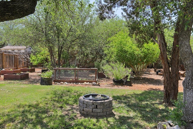 view of yard with a garden, fence, and an outdoor fire pit