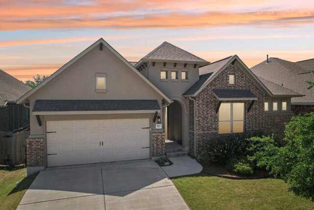view of front of property featuring roof with shingles, concrete driveway, brick siding, an attached garage, and stucco siding