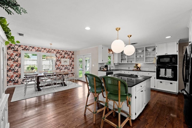 1403 E 16th St, Georgetown, TX 78626 - kitchen featuring black appliances, dark countertops, open shelves, white cabinets, and wallpapered walls