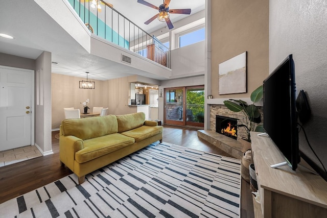 8200 Neely Dr Unit 217, Austin, TX 78759 - living room featuring wood finished floors, a fireplace, a chandelier, a ceiling fan, and a high ceiling