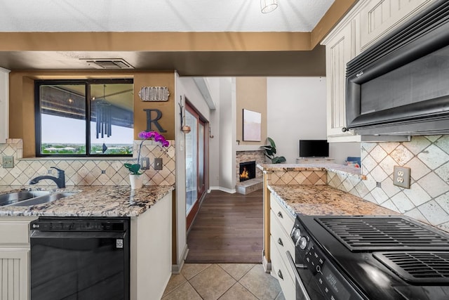 8200 Neely Dr Unit 217, Austin, TX 78759 - kitchen featuring black appliances, a sink, white cabinets, light tile patterned floors, and light stone countertops