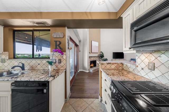 8200 Neely Dr Unit 217, Austin, TX 78759 - kitchen featuring black appliances, a sink, white cabinets, light tile patterned floors, and light stone countertops