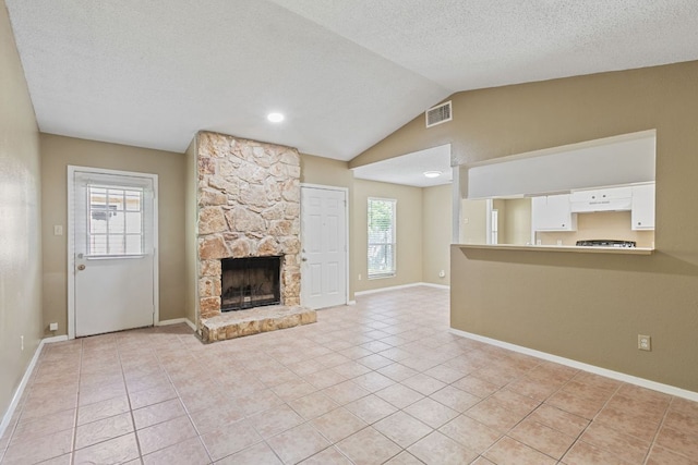 unfurnished living room featuring vaulted ceiling, visible vents, light tile patterned floors, baseboards, and a fireplace