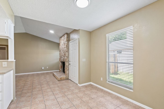 unfurnished living room with vaulted ceiling, light tile patterned flooring, a textured ceiling, and a fireplace