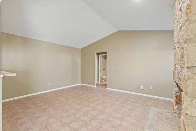 unfurnished room with lofted ceiling, light tile patterned flooring, and baseboards