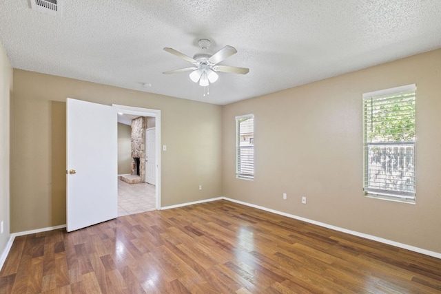 empty room with ceiling fan, a healthy amount of sunlight, wood finished floors, and visible vents
