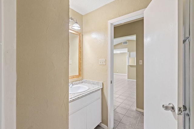 bathroom featuring a textured wall, visible vents, and tile patterned floors
