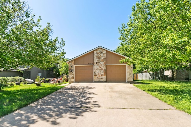 mid-century modern home with stone siding, concrete driveway, fence, a garage, and a front yard