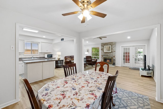 607 Elderberry Cv, Austin, TX 78745 - dining room with a ceiling fan, light wood-style floors, a fireplace, healthy amount of natural light, and recessed lighting