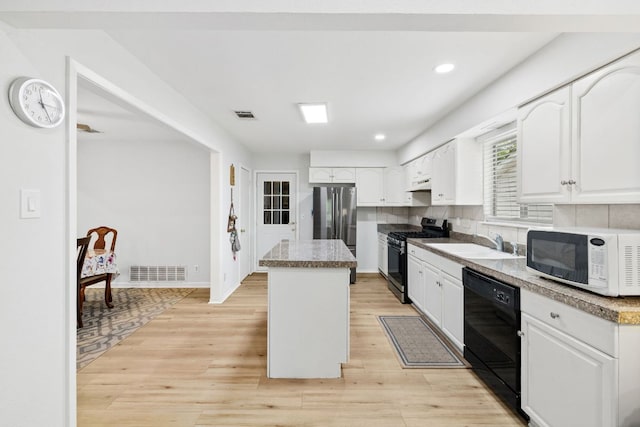 607 Elderberry Cv, Austin, TX 78745 - kitchen with black appliances, a center island, a sink, white cabinets, and recessed lighting