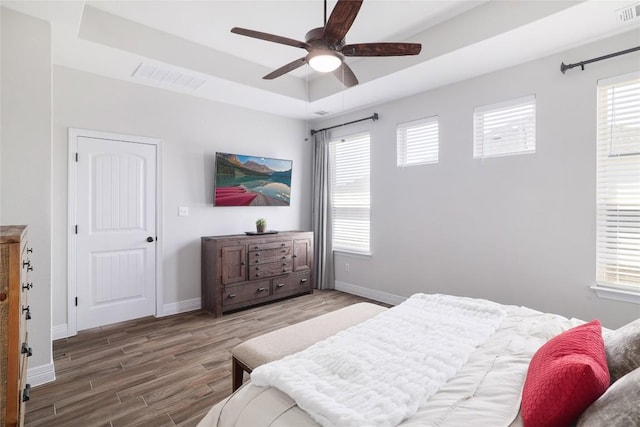 505 Saturnia Dr, Georgetown, TX 78628 - bedroom featuring a raised ceiling, wood finished floors, baseboards, and a ceiling fan