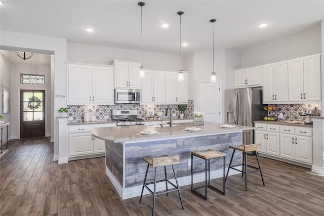 505 Saturnia Dr, Georgetown, TX 78628 - kitchen with stainless steel appliances, a sink, dark wood finished floors, tasteful backsplash, and a kitchen breakfast bar