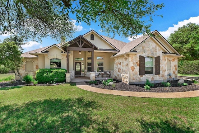 craftsman house featuring roof with shingles, stone siding, a front yard, and stucco siding