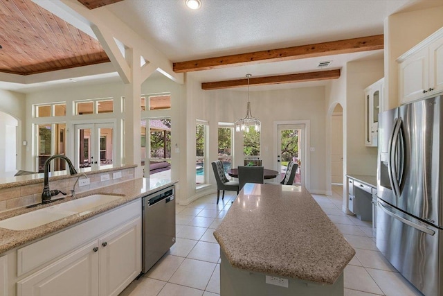 kitchen with white cabinets, arched walkways, appliances with stainless steel finishes, and a sink