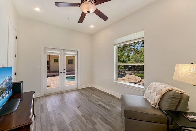 living area with wood finished floors, baseboards, ceiling fan, and french doors