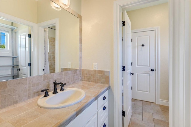 bathroom featuring baseboards, vanity, stone finish flooring, and backsplash