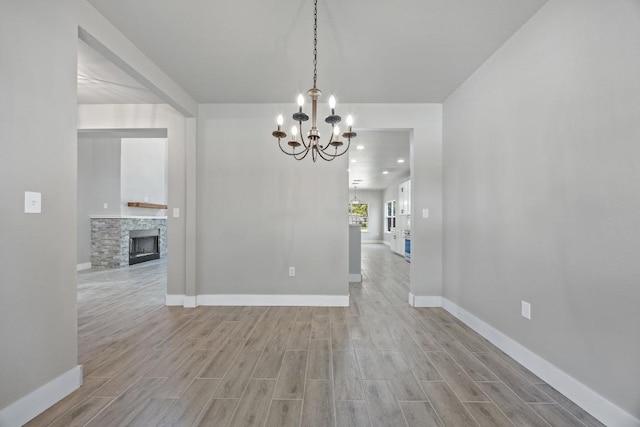 7 Harmony Ln, Wimberley, TX 78676 - unfurnished dining area featuring wood finished floors, a chandelier, and a fireplace