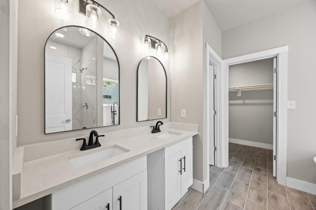 7 Harmony Ln, Wimberley, TX 78676 - full bathroom with a stall shower, double vanity, a spacious closet, and wood finish floors