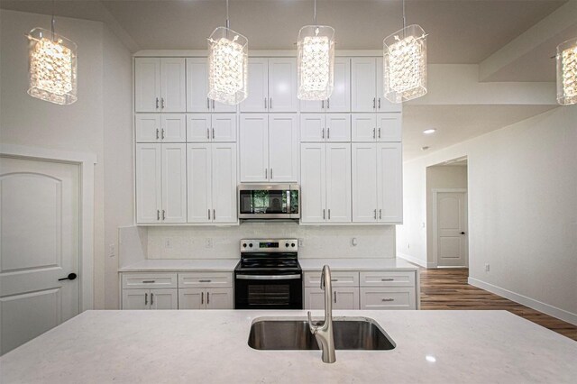 106 Passion Vine Rd, Dale, TX 78616 - kitchen with appliances with stainless steel finishes, white cabinetry, wood finished floors, tasteful backsplash, and decorative light fixtures