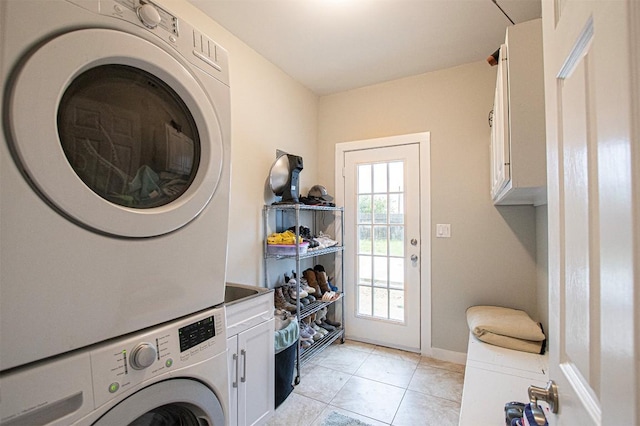 171 Milagros Dr, Cedar Creek, TX 78612 - laundry area featuring stacked washing machine and dryer, cabinet space, and light tile patterned floors
