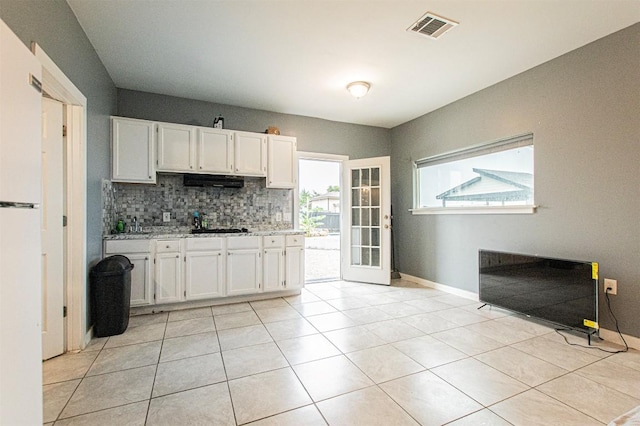 171 Milagros Dr, Cedar Creek, TX 78612 - kitchen with decorative backsplash, white cabinets, freestanding refrigerator, and light tile patterned floors