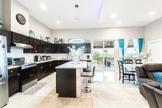 171 Milagros Dr, Cedar Creek, TX 78612 - kitchen featuring stainless steel appliances, under cabinet range hood, open floor plan, a kitchen bar, and light countertops