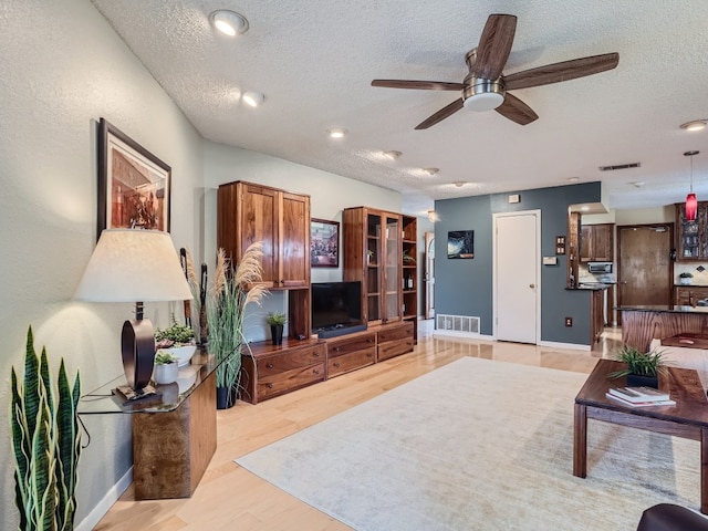 822 Hermitage Dr, Austin, TX 78753 - living room featuring a textured ceiling, a ceiling fan, light wood-style flooring, and baseboards