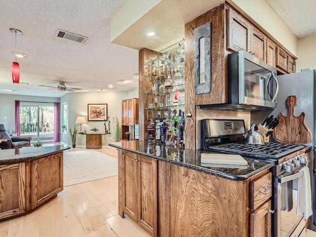 822 Hermitage Dr, Austin, TX 78753 - kitchen featuring appliances with stainless steel finishes, brown cabinets, open floor plan, light wood-type flooring, and a ceiling fan