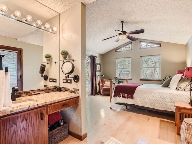 822 Hermitage Dr, Austin, TX 78753 - bedroom with light wood-type flooring, a sink, vaulted ceiling, a textured ceiling, and a ceiling fan