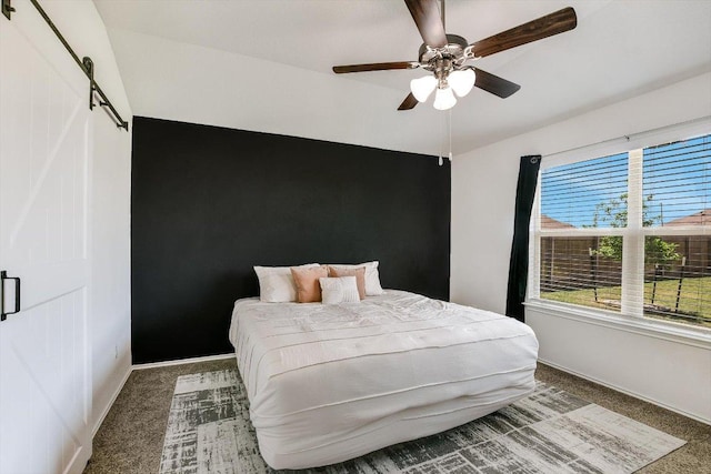 carpeted bedroom featuring a barn door, baseboards, and ceiling fan