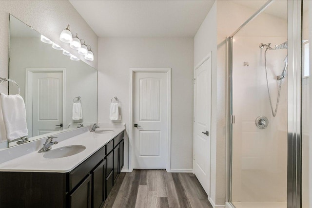 full bathroom featuring wood finished floors, a sink, and a stall shower