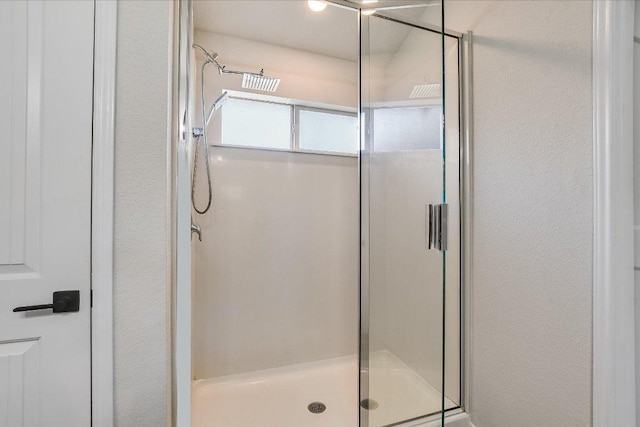 bathroom featuring a textured wall and a shower stall