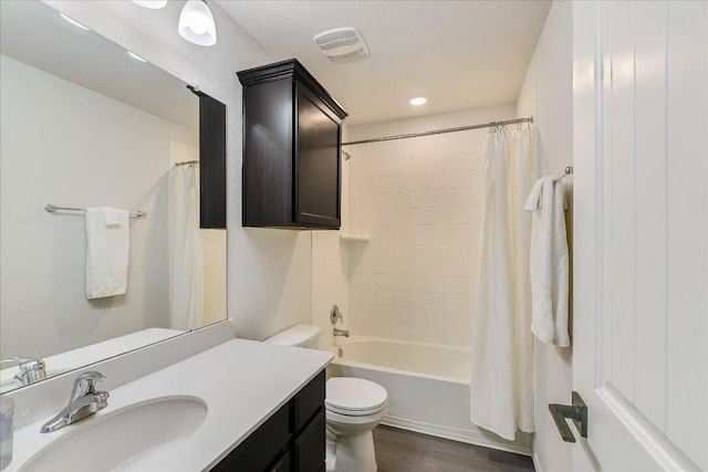 full bathroom with wood finished floors, vanity, shower / tub combo, toilet, and visible vents