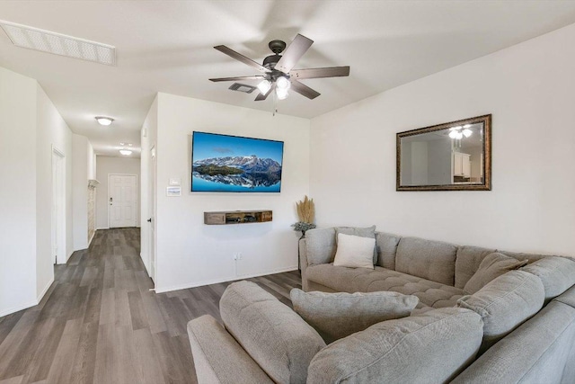 living area featuring dark wood-type flooring, visible vents, baseboards, and ceiling fan