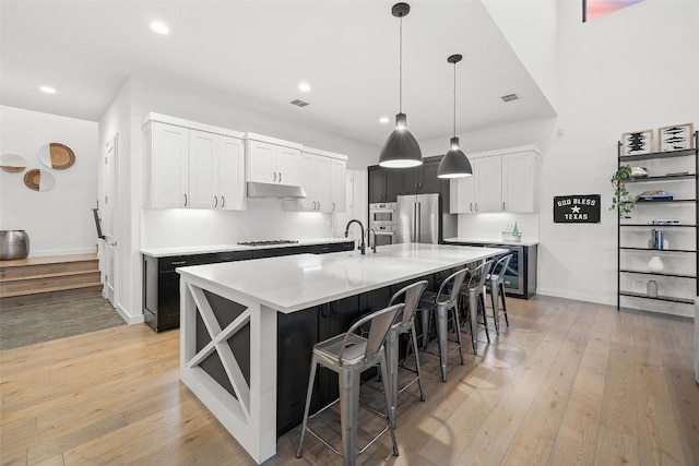 308 Rustling Wake Cv, Lakeway, TX 78738 - kitchen featuring stainless steel appliances, under cabinet range hood, light wood-style flooring, a kitchen breakfast bar, and recessed lighting