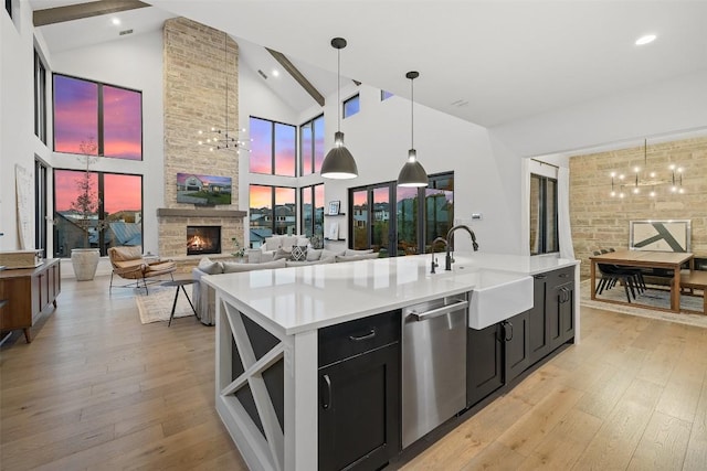 308 Rustling Wake Cv, Lakeway, TX 78738 - kitchen with stainless steel dishwasher, dark cabinets, light countertops, a fireplace, and beam ceiling
