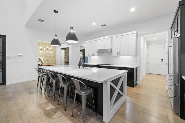 308 Rustling Wake Cv, Lakeway, TX 78738 - kitchen featuring under cabinet range hood, gas cooktop, a kitchen island with sink, light countertops, and recessed lighting