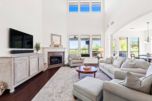 16216 Zagros Way, Austin, TX 78738 - living room featuring arched walkways, dark wood-style floors, a high ceiling, a fireplace, and healthy amount of natural light