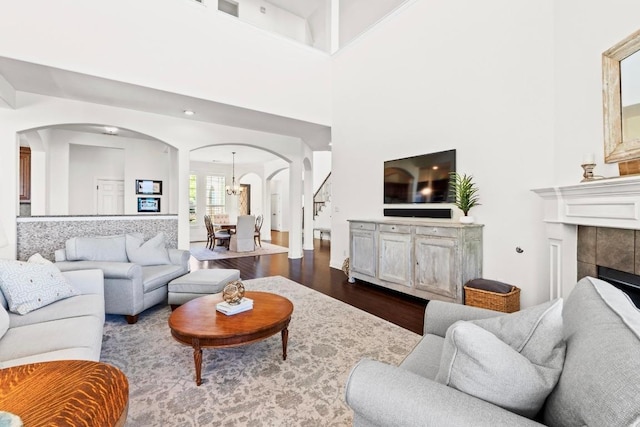 16216 Zagros Way, Austin, TX 78738 - living room featuring arched walkways, dark wood finished floors, a chandelier, a tile fireplace, and a towering ceiling