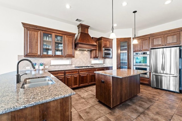 16216 Zagros Way, Austin, TX 78738 - kitchen featuring appliances with stainless steel finishes, custom range hood, light stone countertops, tasteful backsplash, and a center island