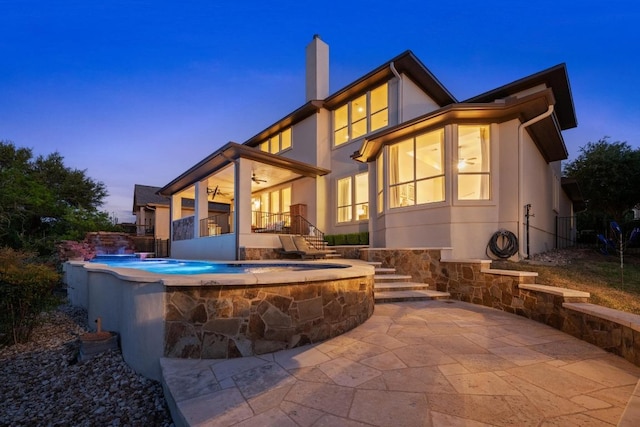 16216 Zagros Way, Austin, TX 78738 - back of house at dusk featuring ceiling fan, a chimney, and stucco siding