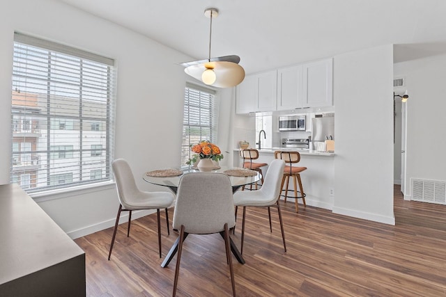 dining room with baseboards, visible vents, and dark wood-style flooring