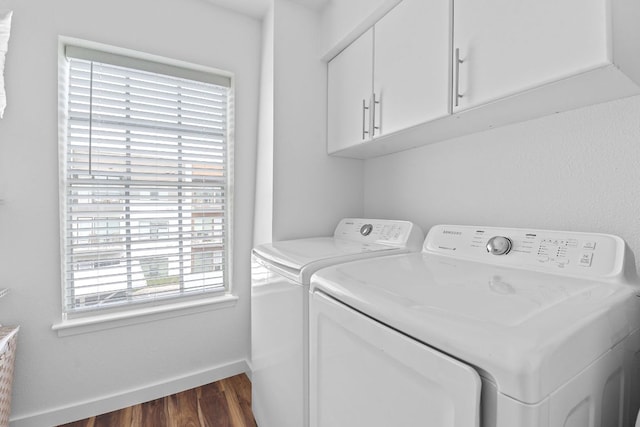 laundry area featuring washing machine and dryer, baseboards, dark wood-type flooring, and cabinet space