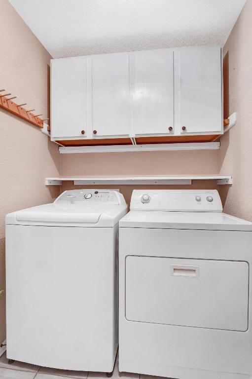 1415 Quicksilver Cir, Round Rock, TX 78665 - laundry area featuring washing machine and clothes dryer, cabinet space, and a textured ceiling