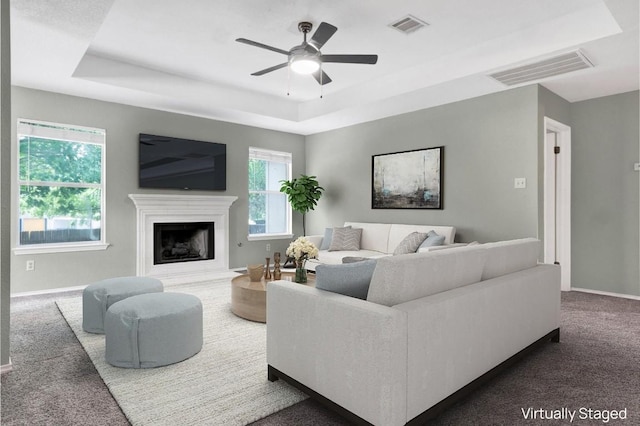 1415 Quicksilver Cir, Round Rock, TX 78665 - carpeted living area featuring a raised ceiling, baseboards, ceiling fan, and a fireplace