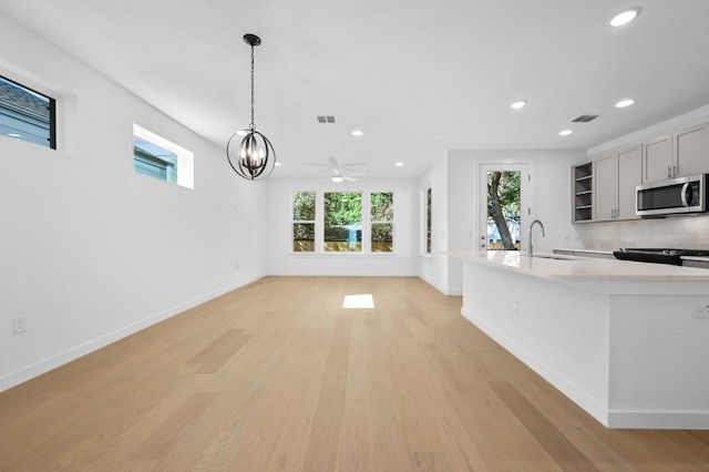 5107 Menchaca Rd Unit 9, Austin, TX 78745 - kitchen featuring stainless steel microwave, light wood finished floors, recessed lighting, light countertops, and decorative light fixtures
