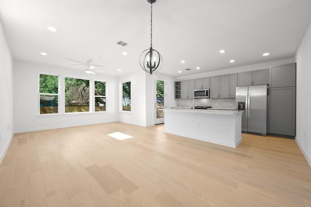 5107 Menchaca Rd Unit 9, Austin, TX 78745 - kitchen featuring appliances with stainless steel finishes, recessed lighting, gray cabinets, light wood-style floors, and a chandelier
