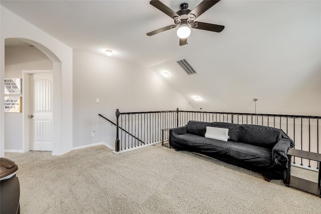 living area with carpet, visible vents, a ceiling fan, an upstairs landing, and arched walkways
